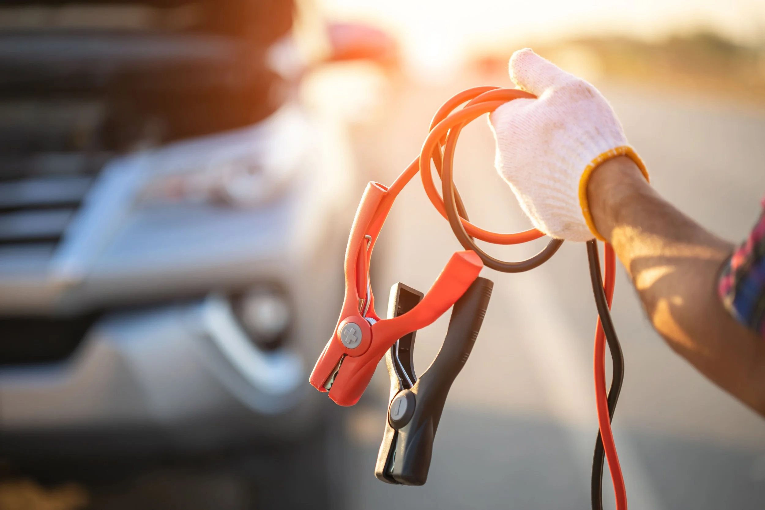 Professional connecting jump start cables to car battery for roadside assistance
